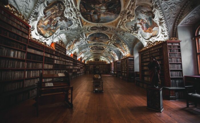 Historische Bibliothek mit kunstvoll verzierten Decken und Bücherregalen.