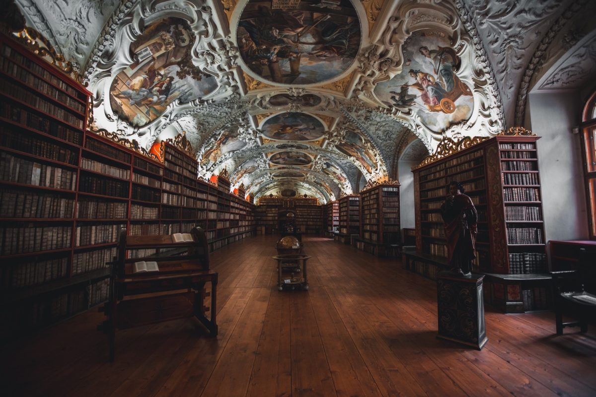 Historische Bibliothek mit kunstvoll verzierten Decken und Bücherregalen.